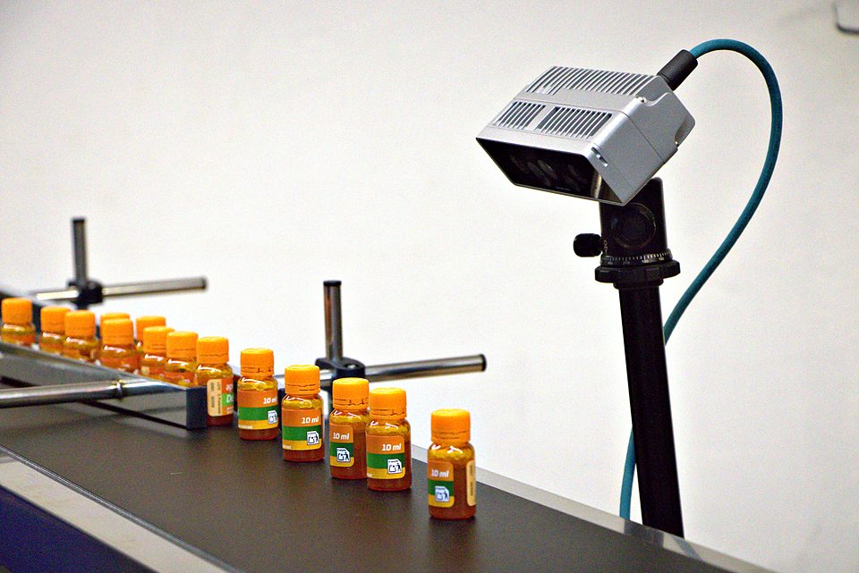 Cámara de visión 3D inspeccionando botes en una cinta transportadora